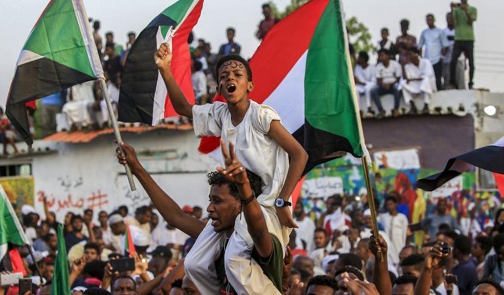 سودانيون يلوحون بأعلام بلدهم خلال الاحتفالات بالاتفاق في الخرطوم (أ.ف.ب)