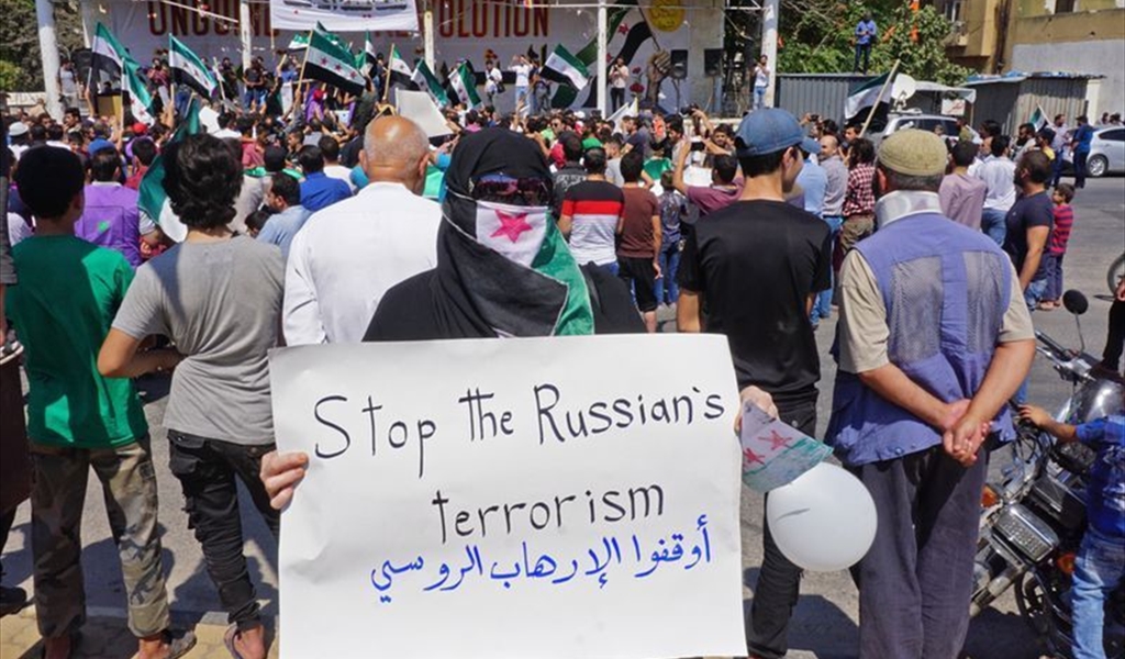 سوري يحمل لافتة تنديدا بالغارات الروسية خلال تظاهرة في إدلب (أ ف ب)