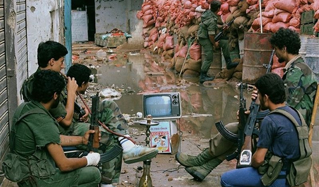 تجتمع لمقاتلين حول تلفزيون صغير يعمل على بطارية سيارة لمتابعة المباراة