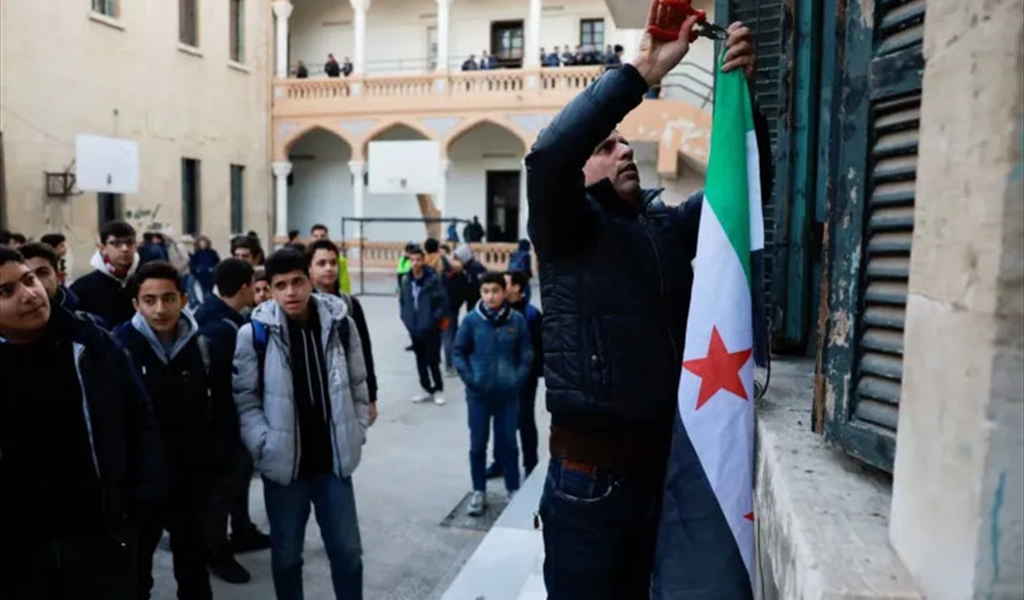طالب يرفع علم الثورة السورية في إحدى مدارس دمشق عقب العودة إلى مقاعد الدراسة