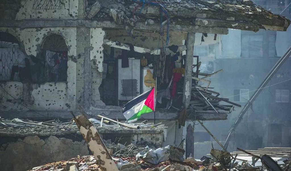 علم فلسطين يرفرف فوق أنقاض مبنى في مخيم جباليا في غزة