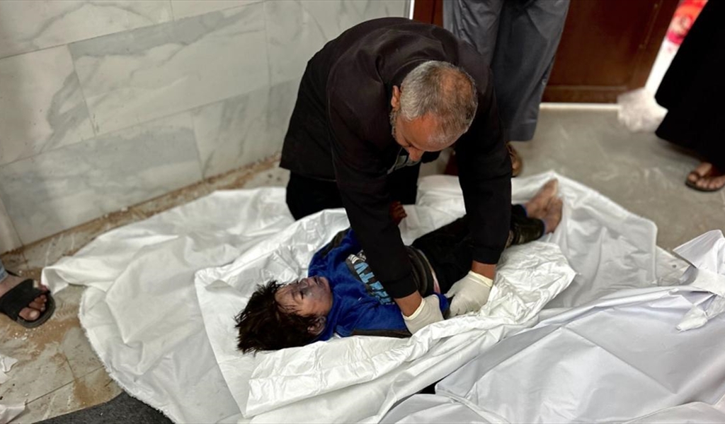 فلسطيني خلال وداع جثمان طفله قبل تكفينه في أحد مستشفيات غزة