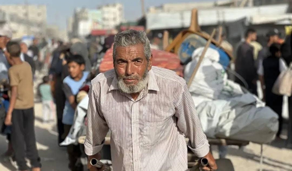مسنّ فلسطيني يجر عربة محملة ببقايا أثاث في غزة