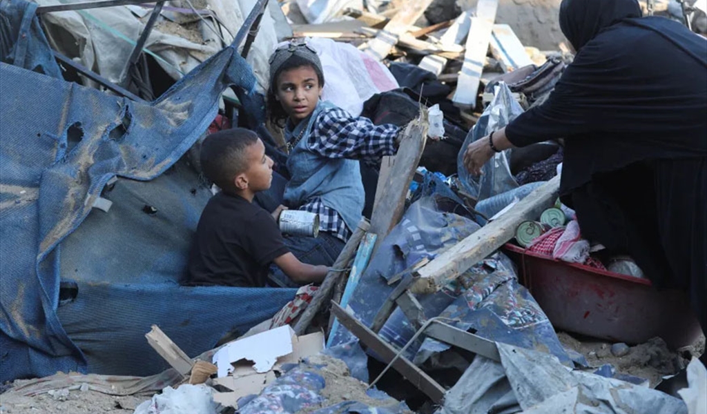 فلسطينية تساعد أطفالها للخروج من بين أنقاض خيمة للنازحين في غزة