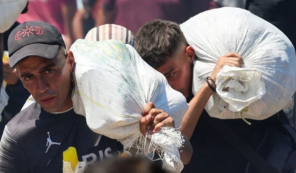 فلسطينيان يحملان أكياس من الدقيق قرب نقطة توزيع مساعدات في رفح