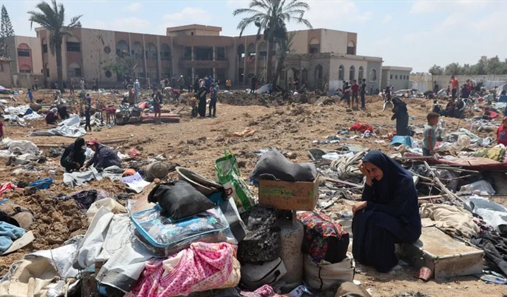 فلسطينية بجوار أغراضها في موقع غارة إسرائيلية على مخيم لإيواء النازحين في دير البلح