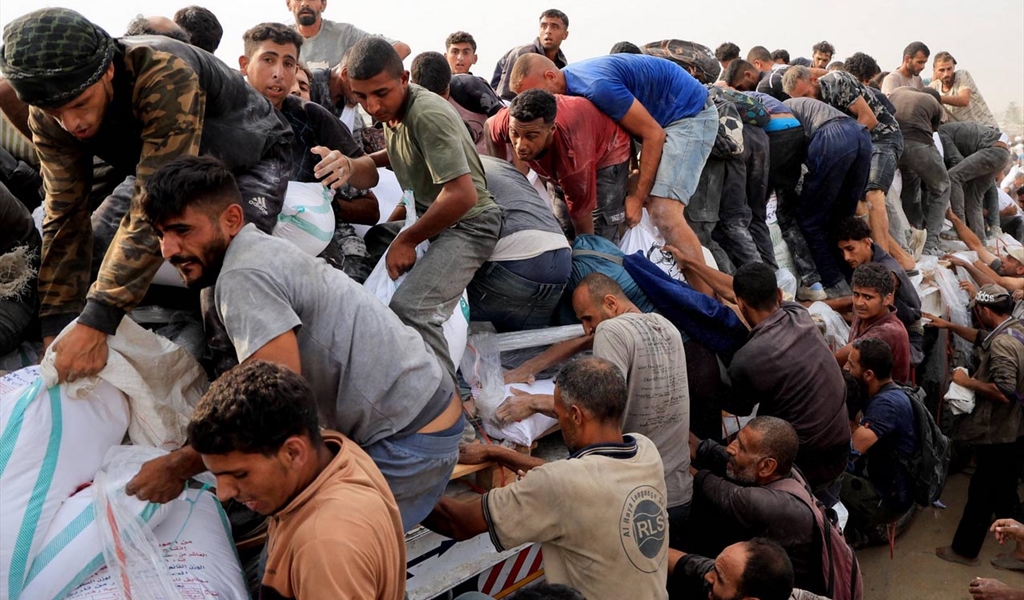 فلسطينيون يعانون من الجوع  والحصار يقفزون على شاحنة مساعدات في خان يونس للحصول على بعض حوائجهم