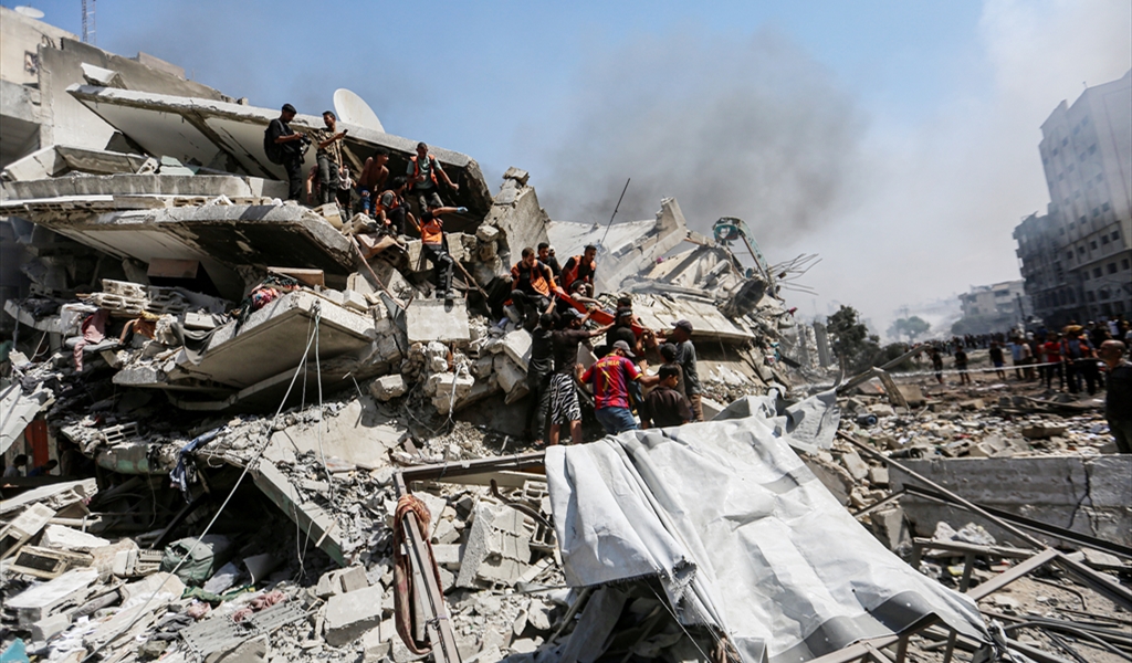 فلسطينيون فوق أنقاض مبنى سكني استهدفته غارة للاحتلال في غزة