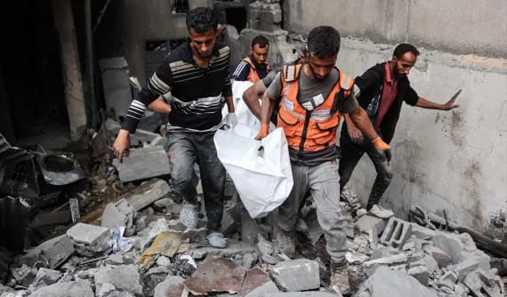 عناصر الدفاع ينتشلون أحد الشهداء في قصف غزة