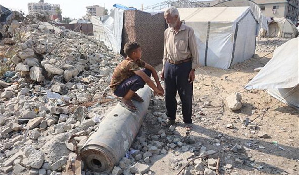 طفل فلسطيني يجلس القرفصاء فوق بقايا صاروخ في غزة
