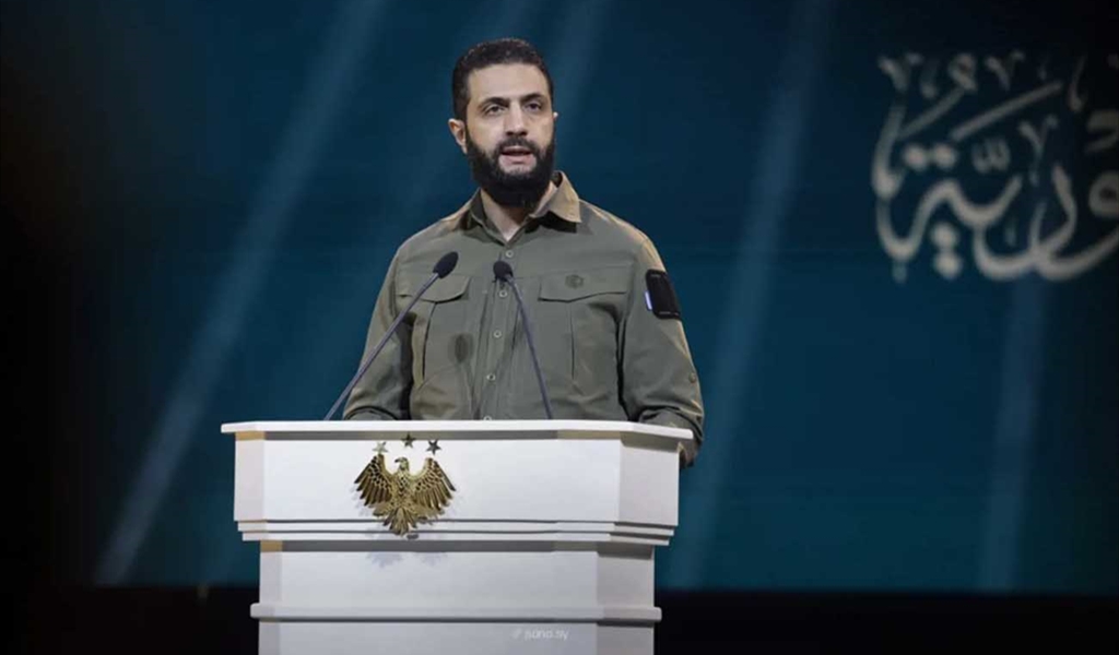 الرئيس الشرع متحدثا بالزي العسكري أثناء الاحتفال في قصر المؤتمرات في دمشق (سانا)