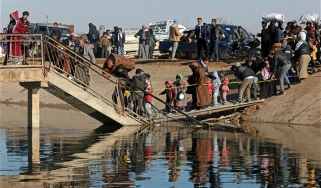 نازحون سوريون من منطقة دير حافر يعبرون جسراً متهالكاً للخروج من المنطقة