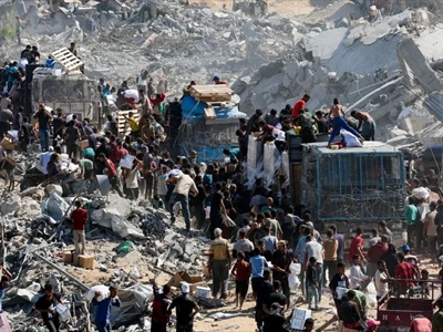 أهالي غزة العائدون يجمعون إمدادات المساعدات من الشاحنات التي دخلت المدينة