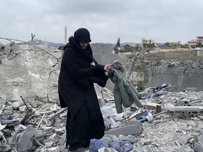 سيدة تحمل ما بقي من القصف في بلدة جرجوع