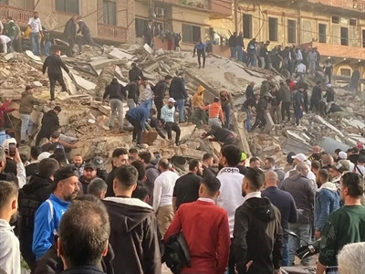 أهالي طرابلس على أنقاض المبنى المنهار، وعمليات البحث عن الأحياء والضحايا مستمرة