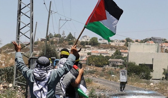 مسنّ يرفع علم فلسطين خلف مجموعة من الشبان خلال مواجهات مع جنود الاحتلال في كفر قدوم بالضفة