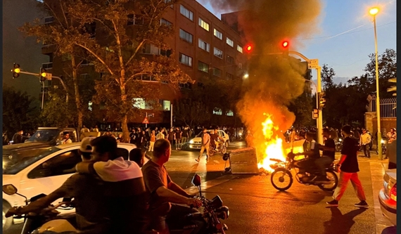 متظاهرون يضرمون النار بدراجة تابعة لأحد عناصر الباسيج في طهران (الجزيرة)
