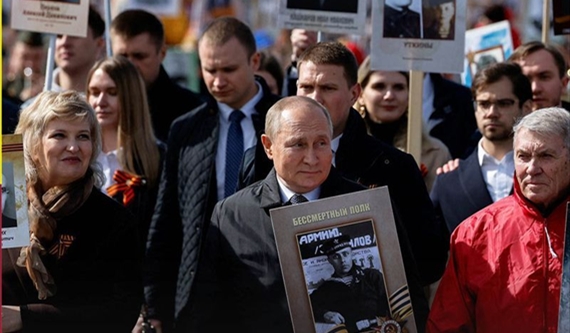 بوتين حاملا صورة والده خلال مشاركته في احتفالات النصر في الساحة الحمراء في موسكو